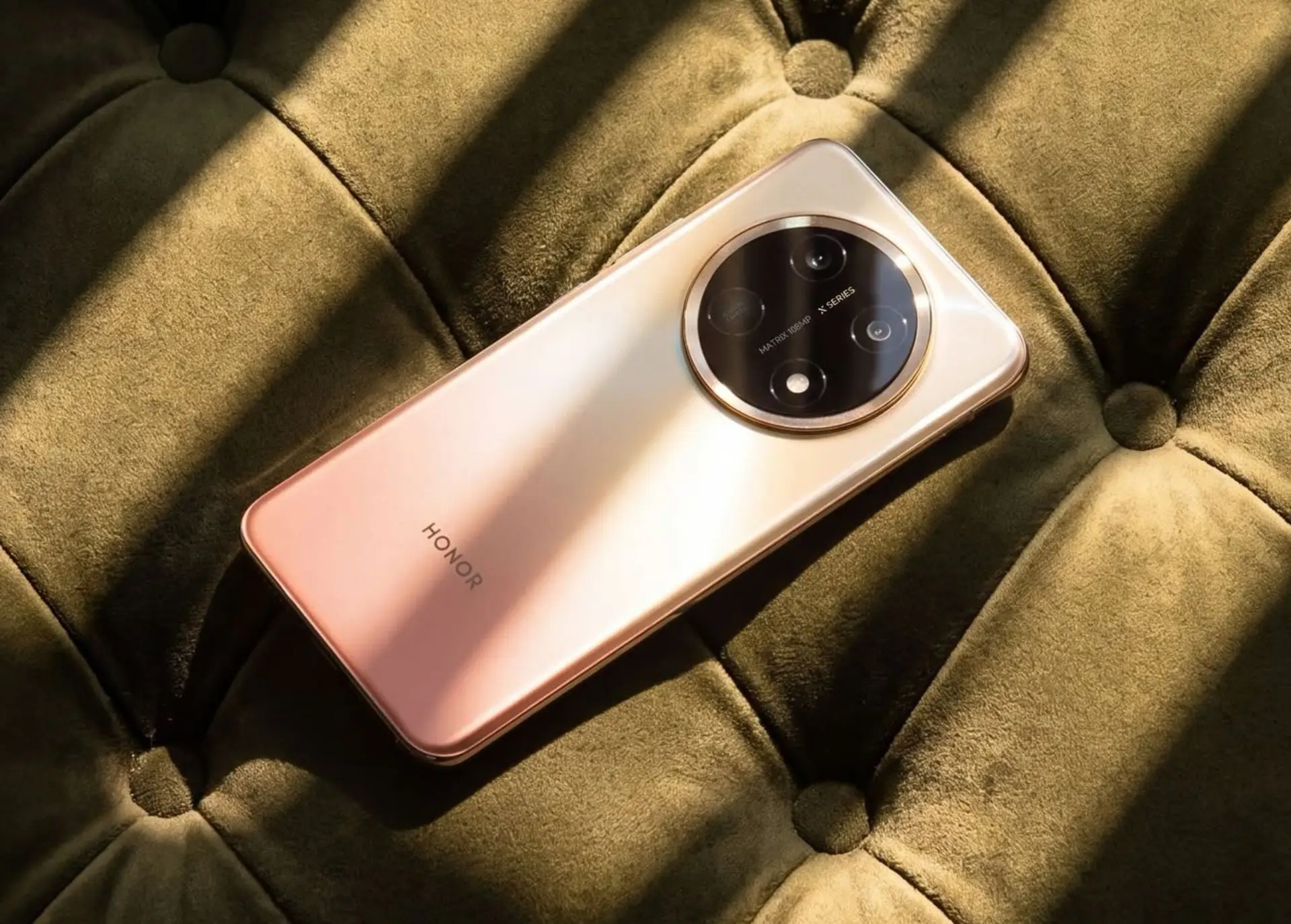 گوشی هوشمند آنر (Honor) X9e Pro با بدنه طلایی روی مبلی سبز